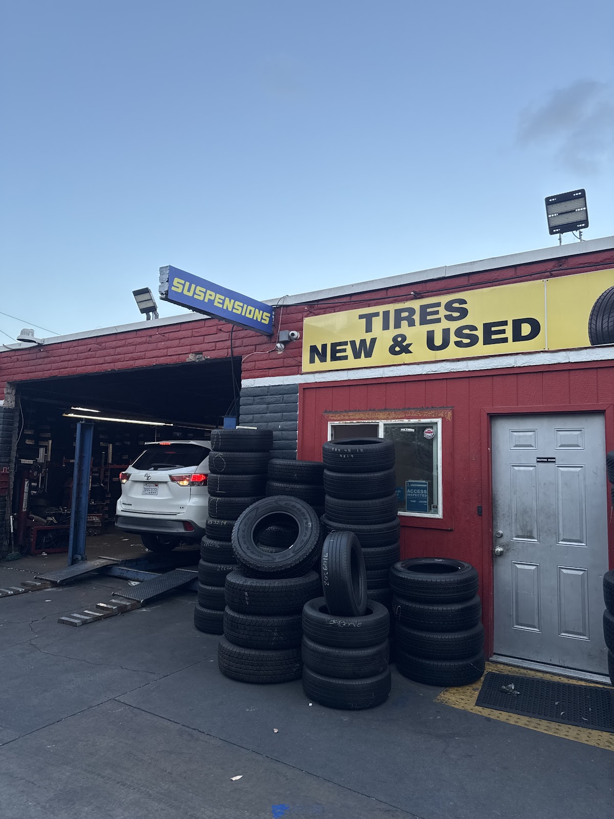 The Whittier Tires shopfront with the TIRES NEW AND USED banner and a car on the lift