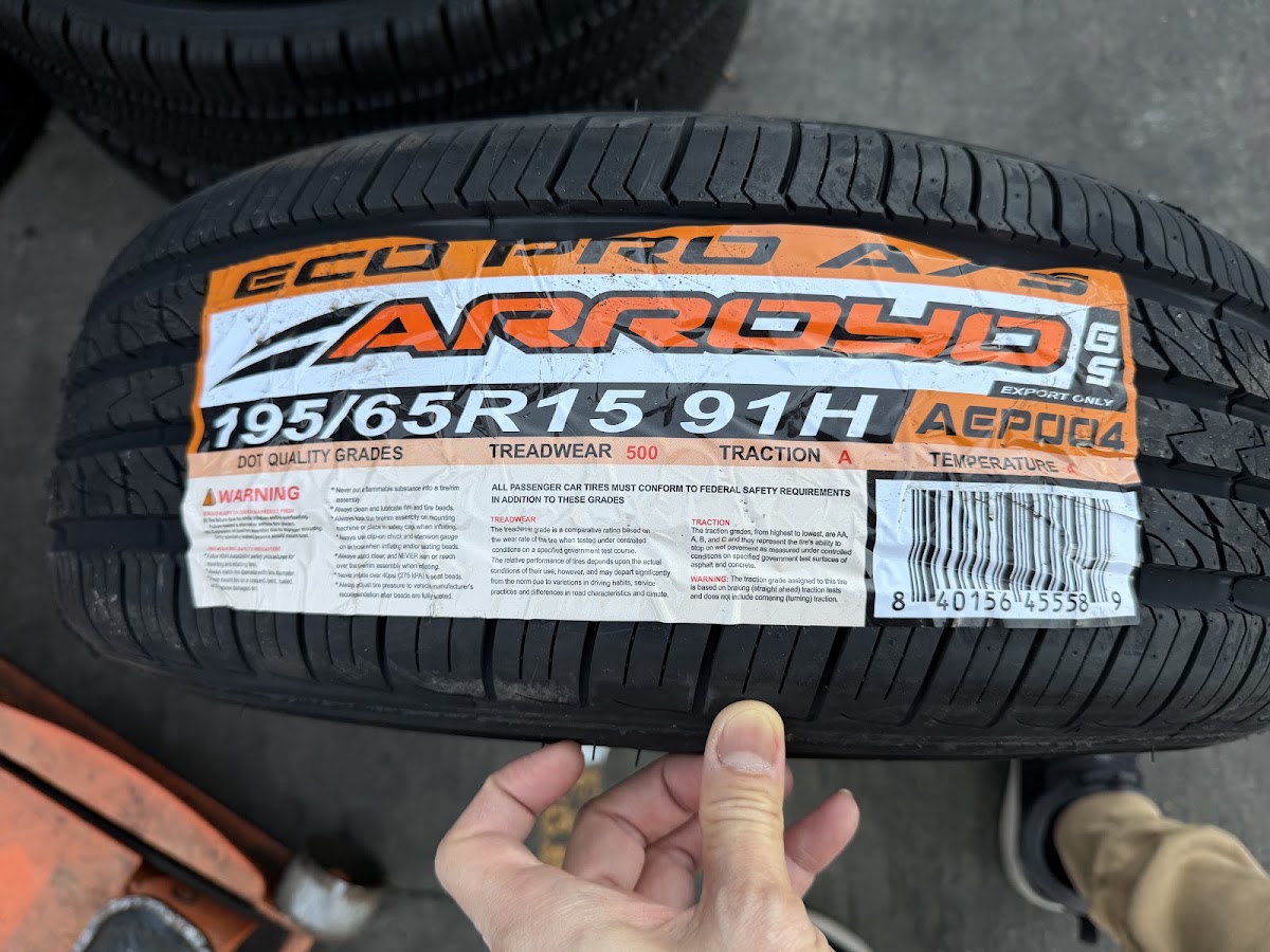 A new tire held up at Whittier Tires with the size and DOT grades printed on the sidewall
