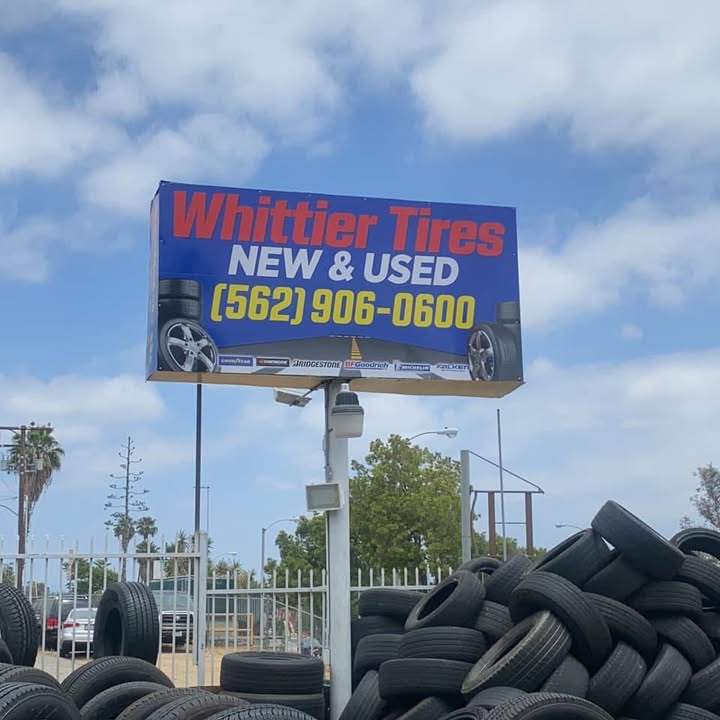 The Whittier Tires roadside sign reading New and Used with the shop phone number, above the tire yard